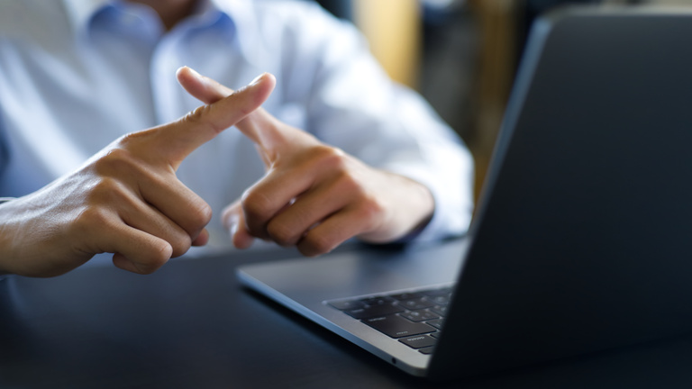 バツのジェスチャーで良くないと伝える男性 a young man gesturing finger crossing meaning negative "NO"